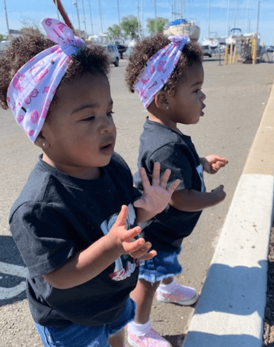 Little girls are wearing baby head wraps featuring a barbie pattern for little girls from By Bella Boutique. Little girls are wearing baby head wraps featuring a barbie pattern for little girls from By Bella Boutique.