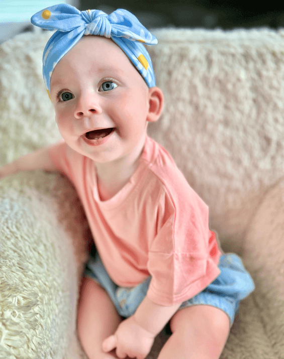 Baby girl is wearing a baby headband featuring a daisy pattern for little girls from By Bella Boutique. Baby girl is wearing a baby headband featuring a daisy pattern for little girls from By Bella Boutique.