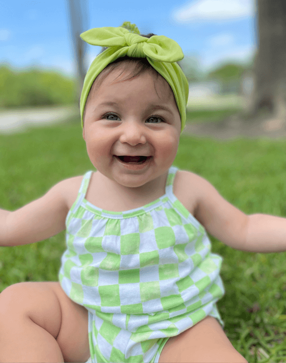 Baby girl is wearing a lime green knot headband for little girls from By Bella Boutique. Baby girl is wearing a lime green knot headband for little girls from By Bella Boutique.