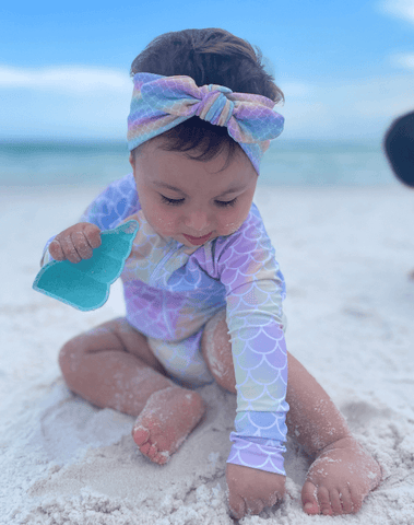 Baby girl is wearing a handmade knot headband featuring a mermaid print from By Bella Boutique. Baby girl is wearing a handmade knot headband featuring a mermaid print from By Bella Boutique.