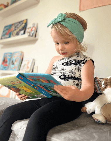 Little girl is wearing a green knotted head wrap from By Bella Boutique. Little girl is wearing a green knotted head wrap from By Bella Boutique.