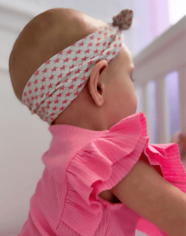Little girl is wearing a knotted headband featuring a starfish print from By Bella Boutique. Little girl is wearing a knotted headband featuring a starfish print from By Bella Boutique.