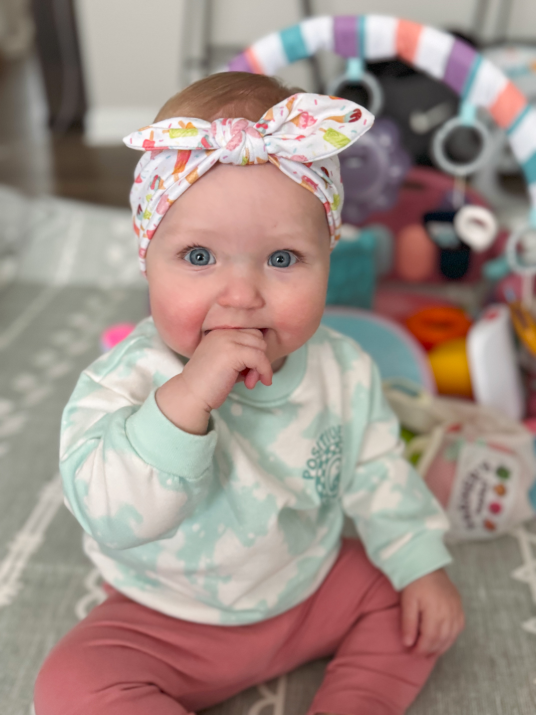 Little girl is wearing a comfortable baby head wrap for little girls from By Bella Boutique. Little girl is wearing a comfortable baby head wrap for little girls from By Bella Boutique.