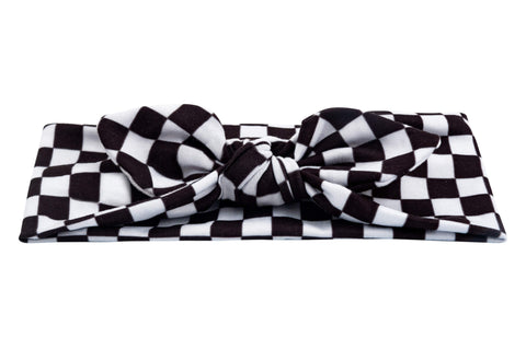 A baby head wrap for little girls featuring a white checkerboard pattern from By Bella Boutique. A baby head wrap for little girls featuring a white checkerboard pattern from By Bella Boutique.