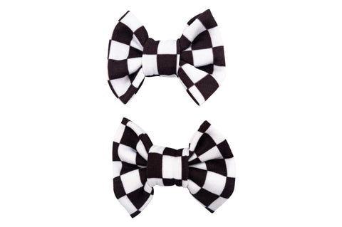 A set of two pigtail bows for toddler girls featuring a white checkerboard pattern from By Bella Boutique. A set of two pigtail bows for toddler girls featuring a white checkerboard pattern from By Bella Boutique.