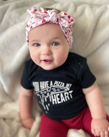 Baby girl is wearing a heart print knot headband for little girls from By Bella Boutique. Baby girl is wearing a heart print knot headband for little girls from By Bella Boutique.