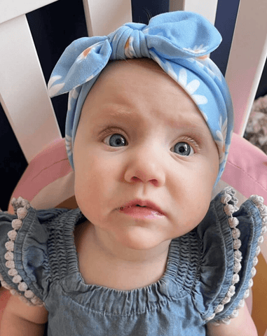 Baby is wearing a top knot headband featuring a daisy pattern for little girls from By Bella Boutique. Baby is wearing a top knot headband featuring a daisy pattern for little girls from By Bella Boutique.