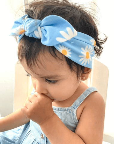 Toddler girl is wearing a handmade knot headband featuring a daisy pattern from By Bella Boutique. Toddler girl is wearing a handmade knot headband featuring a daisy pattern from By Bella Boutique.