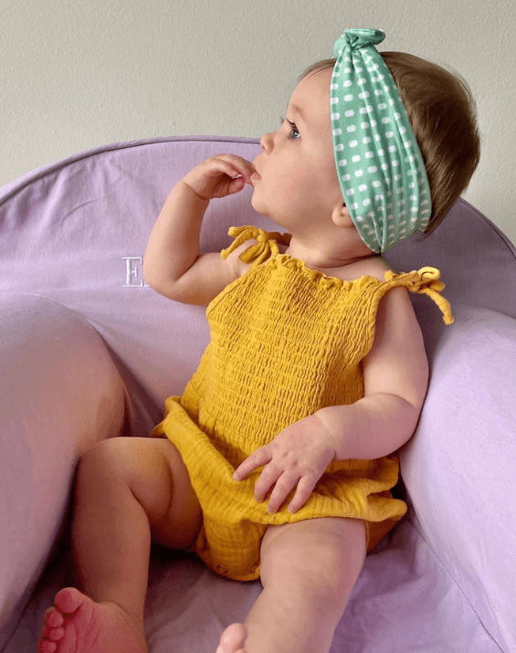 Little girl is wearing a baby head wrap featuring a dot pattern from By Bella Boutique. Little girl is wearing a baby head wrap featuring a dot pattern from By Bella Boutique.