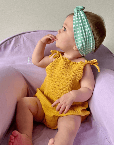 Little girl is wearing a baby head wrap featuring a dot pattern from By Bella Boutique. Little girl is wearing a baby head wrap featuring a dot pattern from By Bella Boutique.
