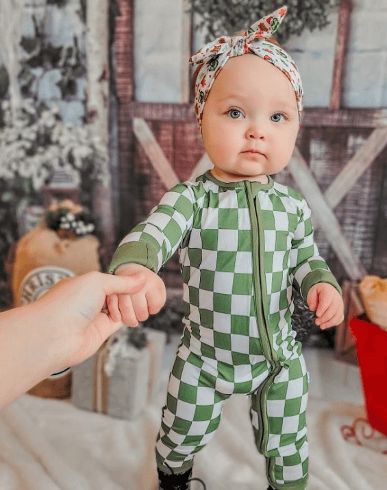 Baby girl is wearing a comfortable knot headband featuring a grinch pattern for little girls from By Bella Boutique. Baby girl is wearing a comfortable knot headband featuring a grinch pattern for little girls from By Bella Boutique.