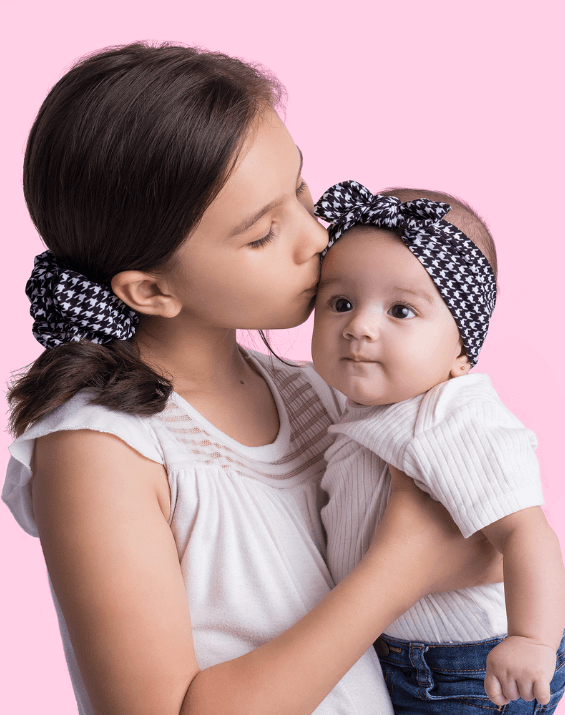 Baby girl is wearing a comfortable baby head wrap featuring a houndstooth pattern from By Bella Boutique. Baby girl is wearing a comfortable baby head wrap featuring a houndstooth pattern from By Bella Boutique.