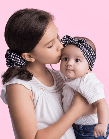 Baby girl is wearing a comfortable baby head wrap featuring a houndstooth pattern from By Bella Boutique. Baby girl is wearing a comfortable baby head wrap featuring a houndstooth pattern from By Bella Boutique.