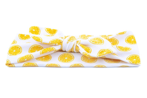A baby head wrap featuring a lemon pattern from By Bella Boutique. A baby head wrap featuring a lemon pattern from By Bella Boutique.