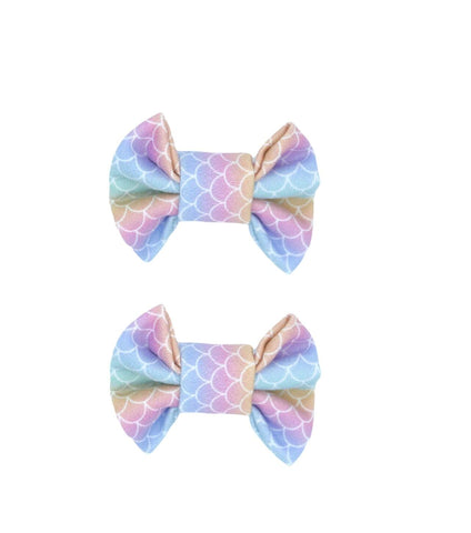 A set of two mermaid print bow clips for toddler girls from By Bella Boutique. A set of two mermaid print bow clips for toddler girls from By Bella Boutique.
