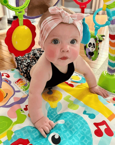 Baby girl is wearing a knotted headband featuring a gingham pattern from By Bella Boutique. Baby girl is wearing a knotted headband featuring a gingham pattern from By Bella Boutique.