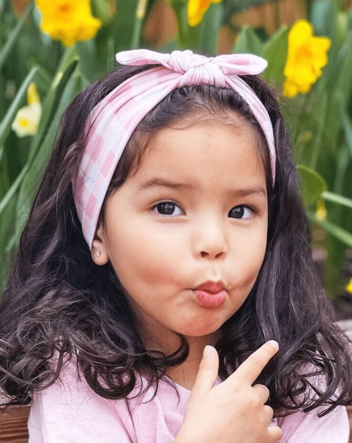 Toddler girl is wearing a pink gingham print top knot headband from By Bella Boutique. Toddler girl is wearing a pink gingham print top knot headband from By Bella Boutique.