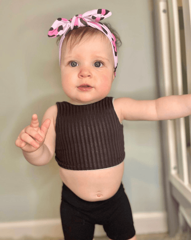 Baby girl is wearing a baby head wrap featuring a leopard print for little girls from By Bella Boutique. Baby girl is wearing a baby head wrap featuring a leopard print for little girls from By Bella Boutique.