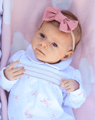 Newborn girl is wearing a pink nylon headband for newborn from By Bella Boutique. Newborn girl is wearing a pink nylon headband for newborn from By Bella Boutique.
