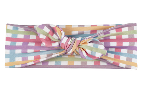 A handmade knotted headband featuring a plaid pattern for little girls from By Bella Boutique. A handmade knotted headband featuring a plaid pattern for little girls from By Bella Boutique.