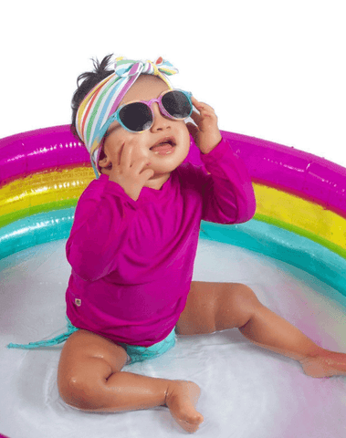 Baby girl is wearing a knotted head wrap featuring a rainbow pattern for little girls from By Bella Boutique. Baby girl is wearing a knotted head wrap featuring a rainbow pattern for little girls from By Bella Boutique.