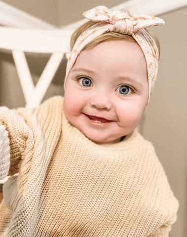 Baby girl is wearing a knotted head wrap featuring a bee pattern for little girls from By Bella Boutique. Baby girl is wearing a knotted head wrap featuring a bee pattern for little girls from By Bella Boutique.