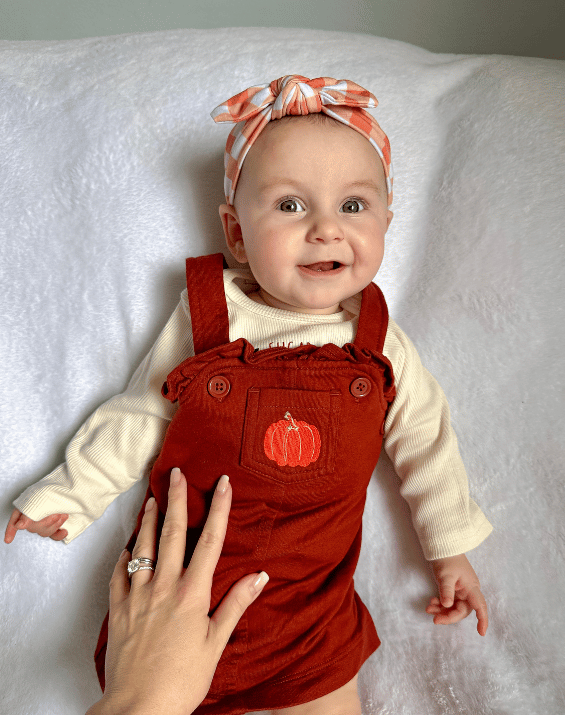 Baby girl is wearing a comfortable baby headband featuring a gingham pattern from By Bella Boutique.