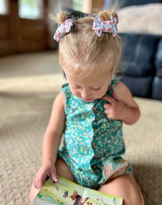 Little girl is wearing a pair of bow clips for toddler girls from By Bella Boutique.