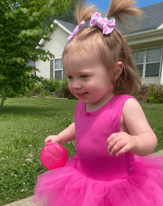 Toddler girl is wearing a set of handmade clip bows for little girls from By Bella Boutique.