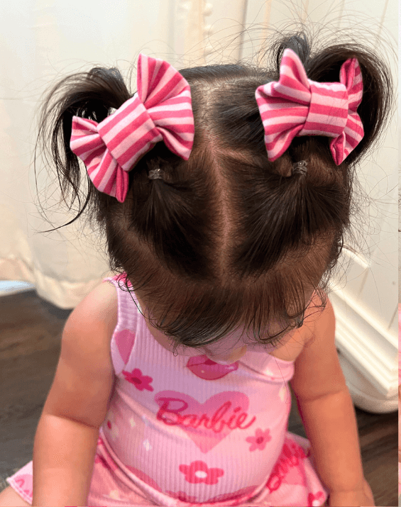 Toddler girl is wearing a set of handmade bow clips for little girls from By Bella Boutique.