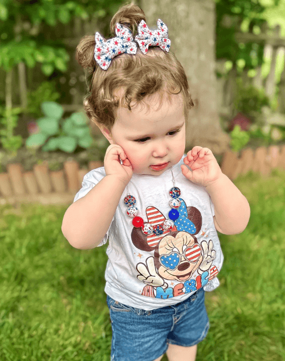 Toddler girl is wearing a set of handmade clip bows for little girls from By Bella Boutique.