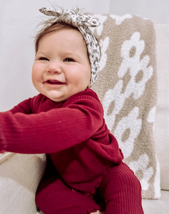 Little girl is wearing a comfortable baby headband for little girls from By Bella Boutique.