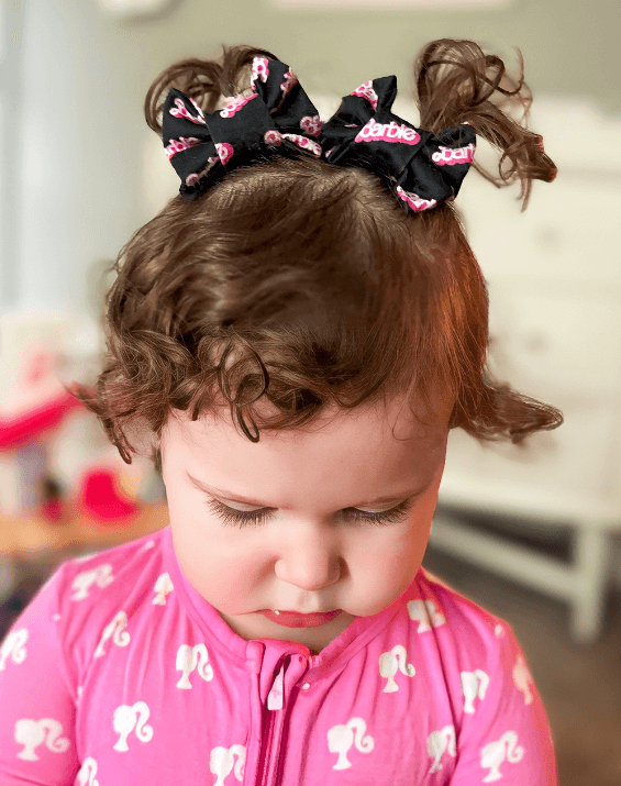 Toddler girl is wearing a pair of handmade clip bows for little girls from By Bella Boutique.
