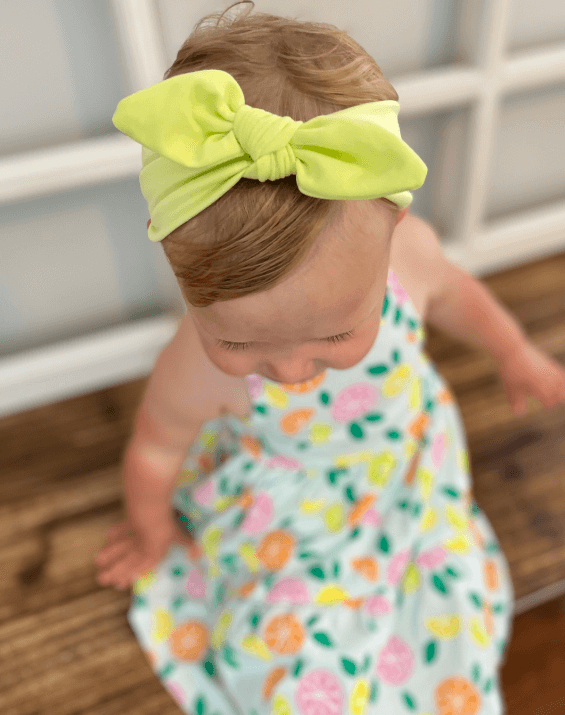 Baby girl is wearing a comfortable baby headwrap for little girls from By Bella Boutique.