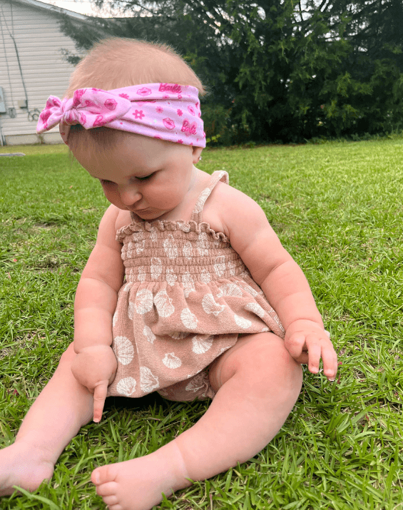 Baby girl is wearing a comfortable baby headband for little girls from By Bella Boutique.