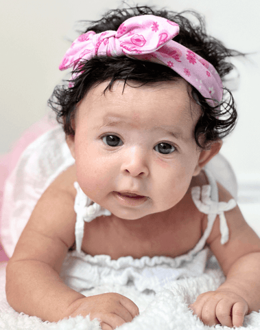 Baby girl is wearing a comfortable baby headband for little girls from By Bella Boutique.