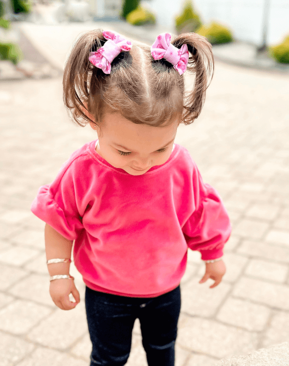 Little girl is wearing a pair of handmade clip bows for toddler girls from By Bella Boutique.