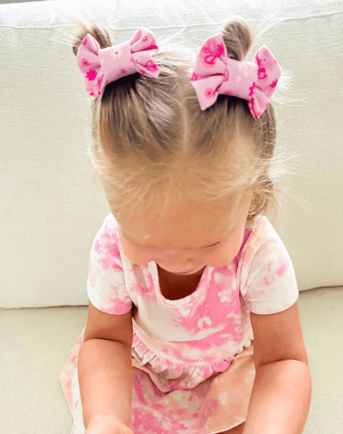Toddler girl is wearing a set of handmade clip bows for toddler girls from By Bella Boutique.