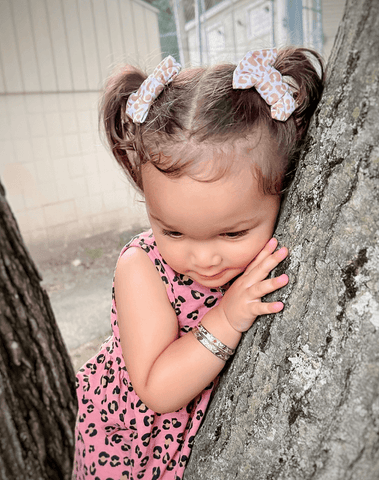Little girl is wearing a set of handmade bow clips for toddler girls from By Bella Boutique.