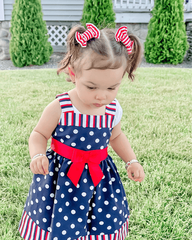 Toddler girl is wearing a set of handmade clip bows for little girls from By Bella Boutique.