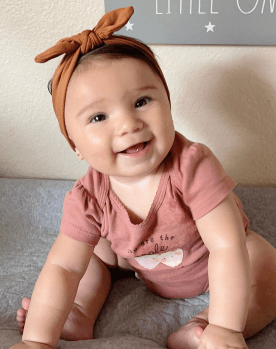 Little girl is wearing a comfortable baby head wrap for little girls from By Bella Boutique.