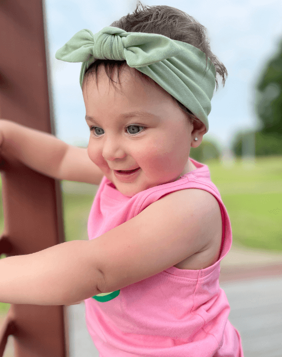 Little girl is wearing a comfortable baby headband for little girls from By Bella Boutique.