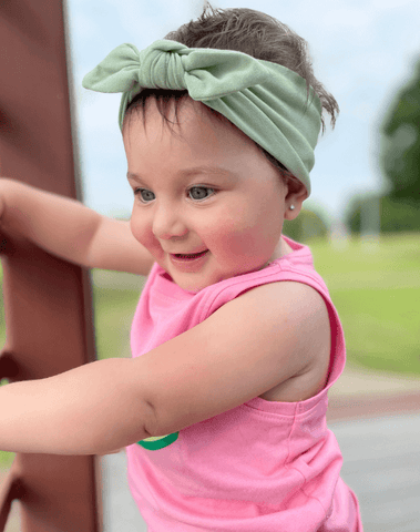 Little girl is wearing a comfortable baby headband for little girls from By Bella Boutique.