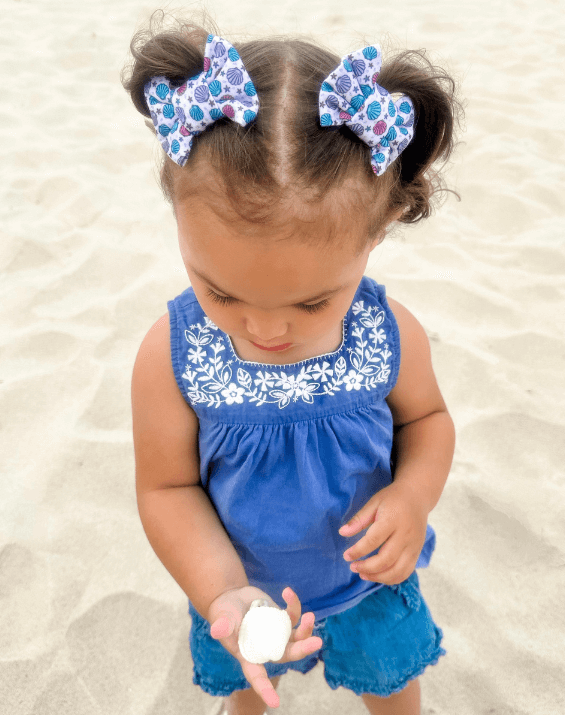 Little girl is wearing a pair of handmade clip bows for toddler girls from By Bella Boutique.