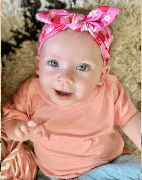 Little girl is wearing a soft baby headband for little girls from By Bella Boutique.