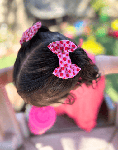 Baby girl is wearing handmade clip bows for toddler girls from By Bella Boutique.