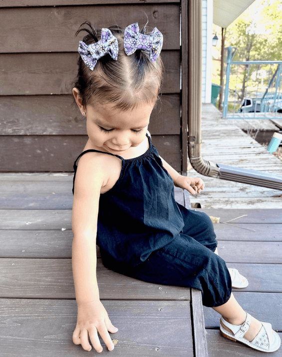 Toddler girl is wearing a set of handmade clip bows from By Bella Boutique.