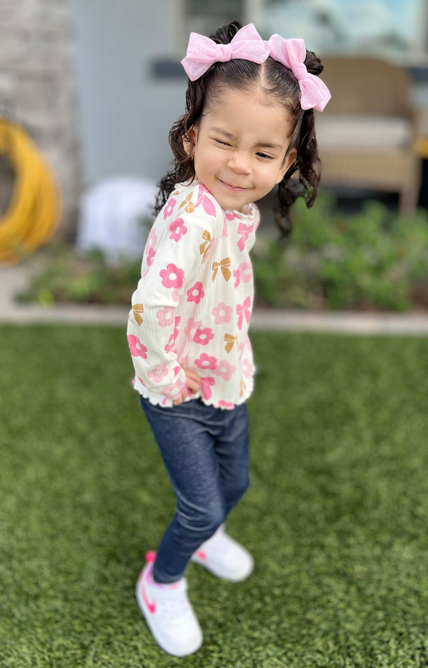 Little girl wearing pink bow clips, smiling over her shoulder