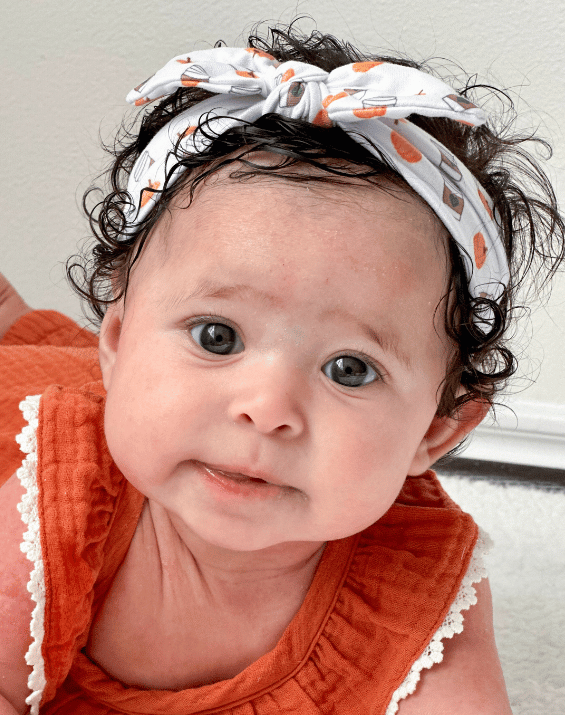 Little girl is wearing a comfortable baby headband for little girls from By Bella Boutique.