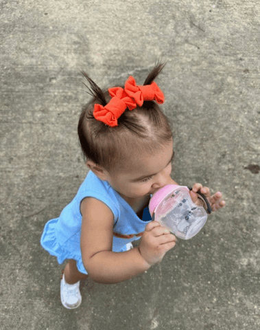 Little girl is wearing a set of handmade bow clips for toddler girls from By Bella Boutique.